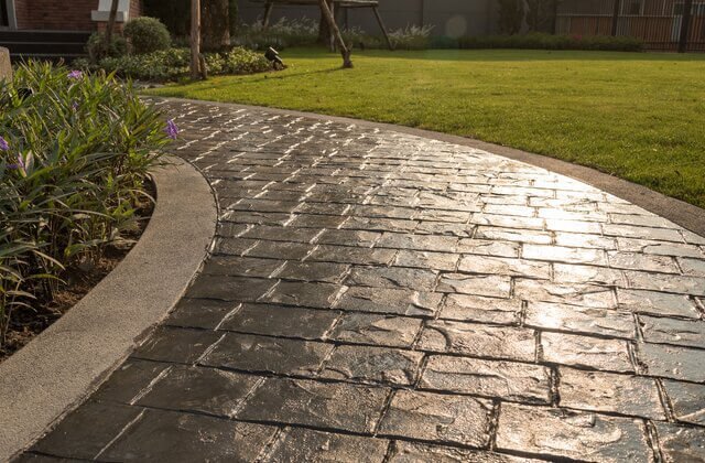 Stamped concrete driveway next to grass yard.
